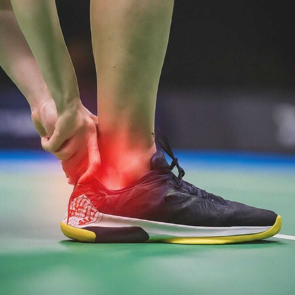 A person's foot in a badminton shoe, emphasizing the potential for foot injuries in badminton.