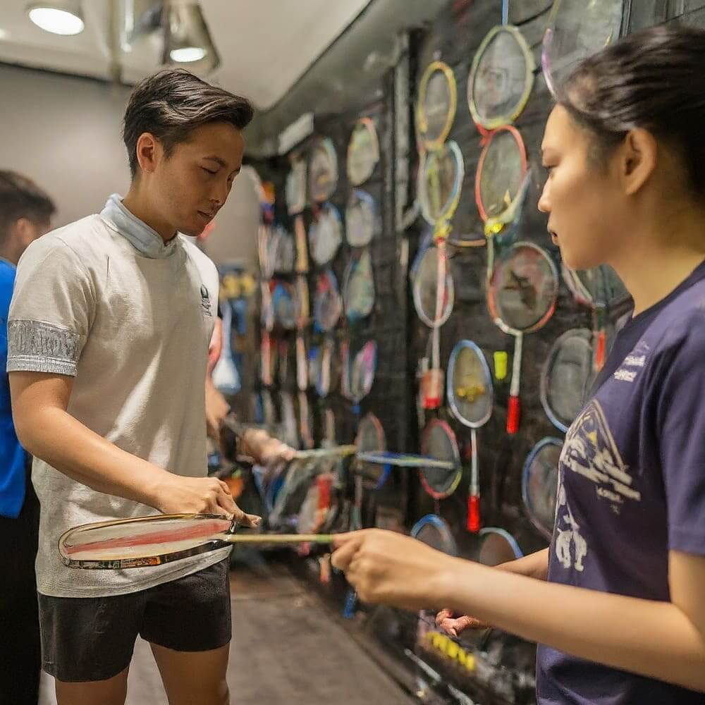 A man and woman selecting rackets at a badminton shop